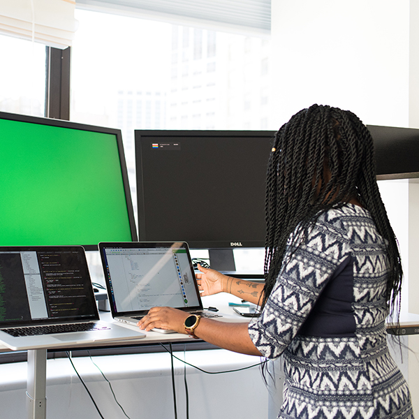 CUNY SPS receives grant to improve computer system Female IT worker on laptop with two monitors