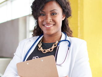 Nursing Organizational Leadership Nurse in white coat and stethoscope holding a clipboard smiling at the camera.