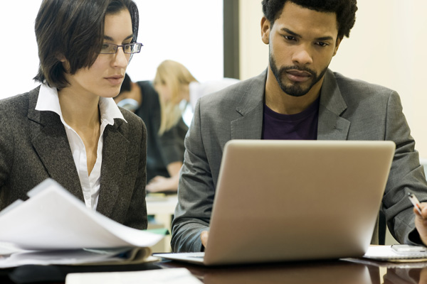 Research Administration and Compliance Man and woman professionals reviewing work on laptop